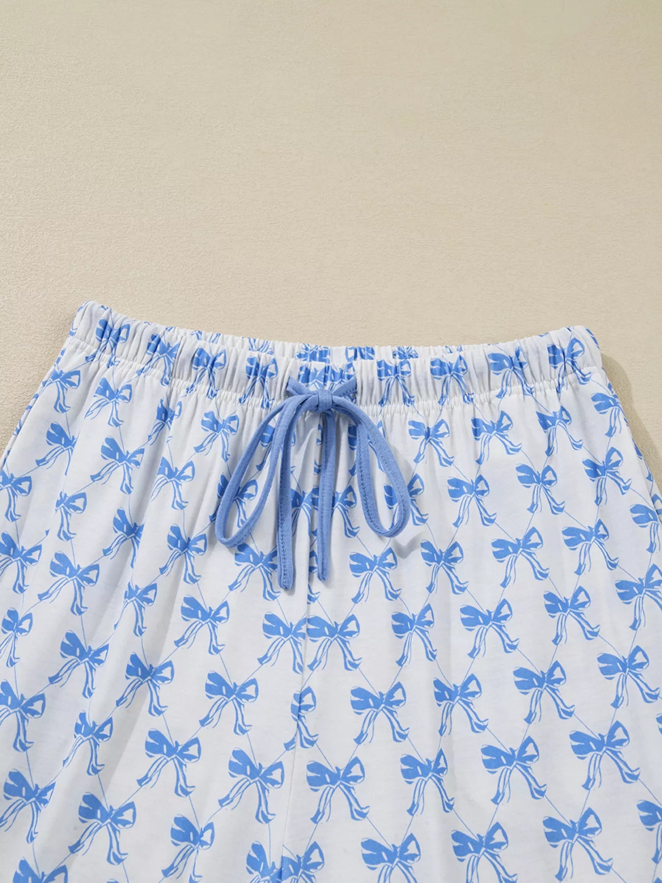 Women’s two-piece pajama set with blue bow print, button-down top, and drawstring pants, cozy and stylish sleepwear.