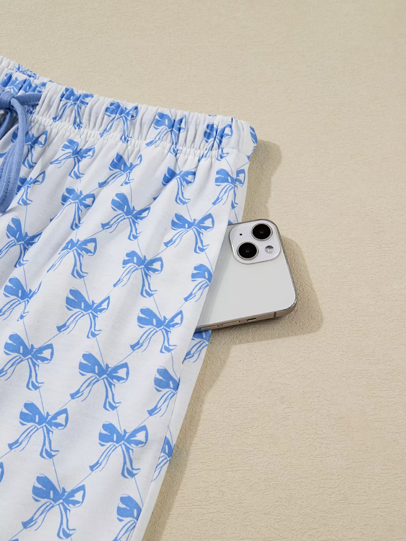 Women’s two-piece pajama set with blue bow print, button-down top, and drawstring pants, cozy and stylish sleepwear.