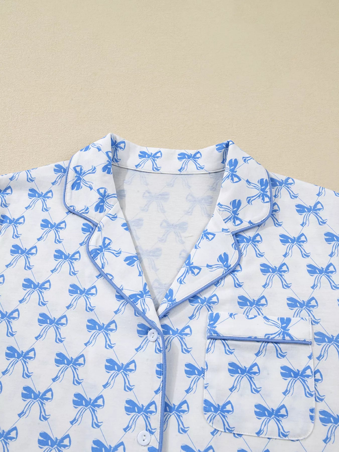 Women’s two-piece pajama set with blue bow print, button-down top, and drawstring pants, cozy and stylish sleepwear.