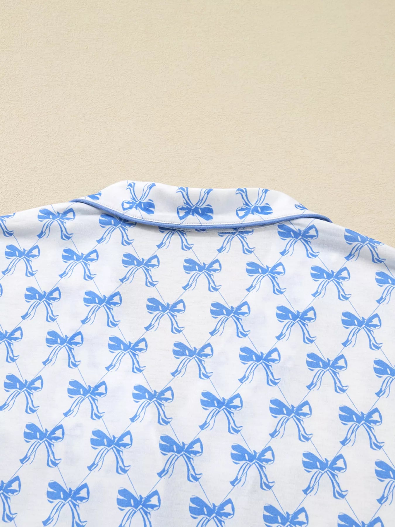 Women’s two-piece pajama set with blue bow print, button-down top, and drawstring pants, cozy and stylish sleepwear.