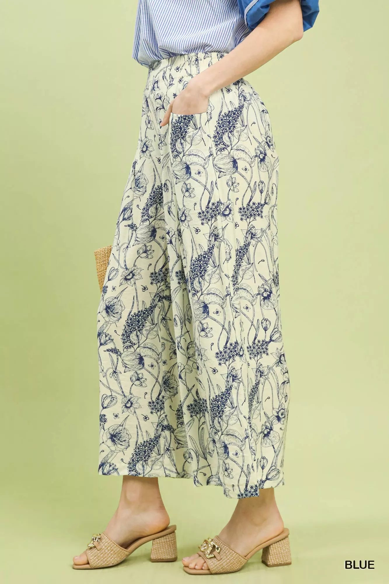 Wide-leg pants with blue botanical floral print, pleated design, elastic waistband, and relaxed fit on a light background