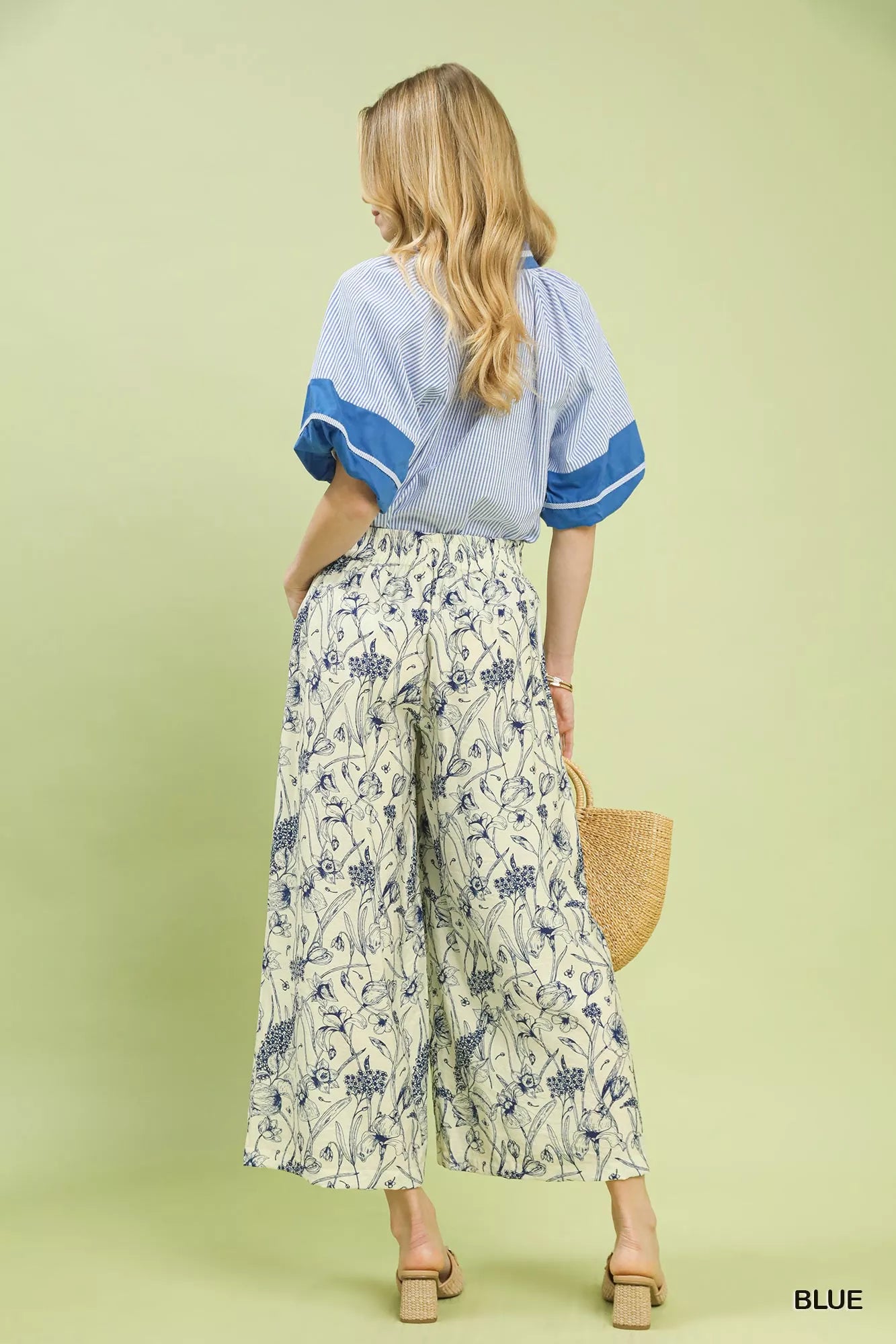Wide-leg pants with blue botanical floral print, pleated design, elastic waistband, and relaxed fit on a light background