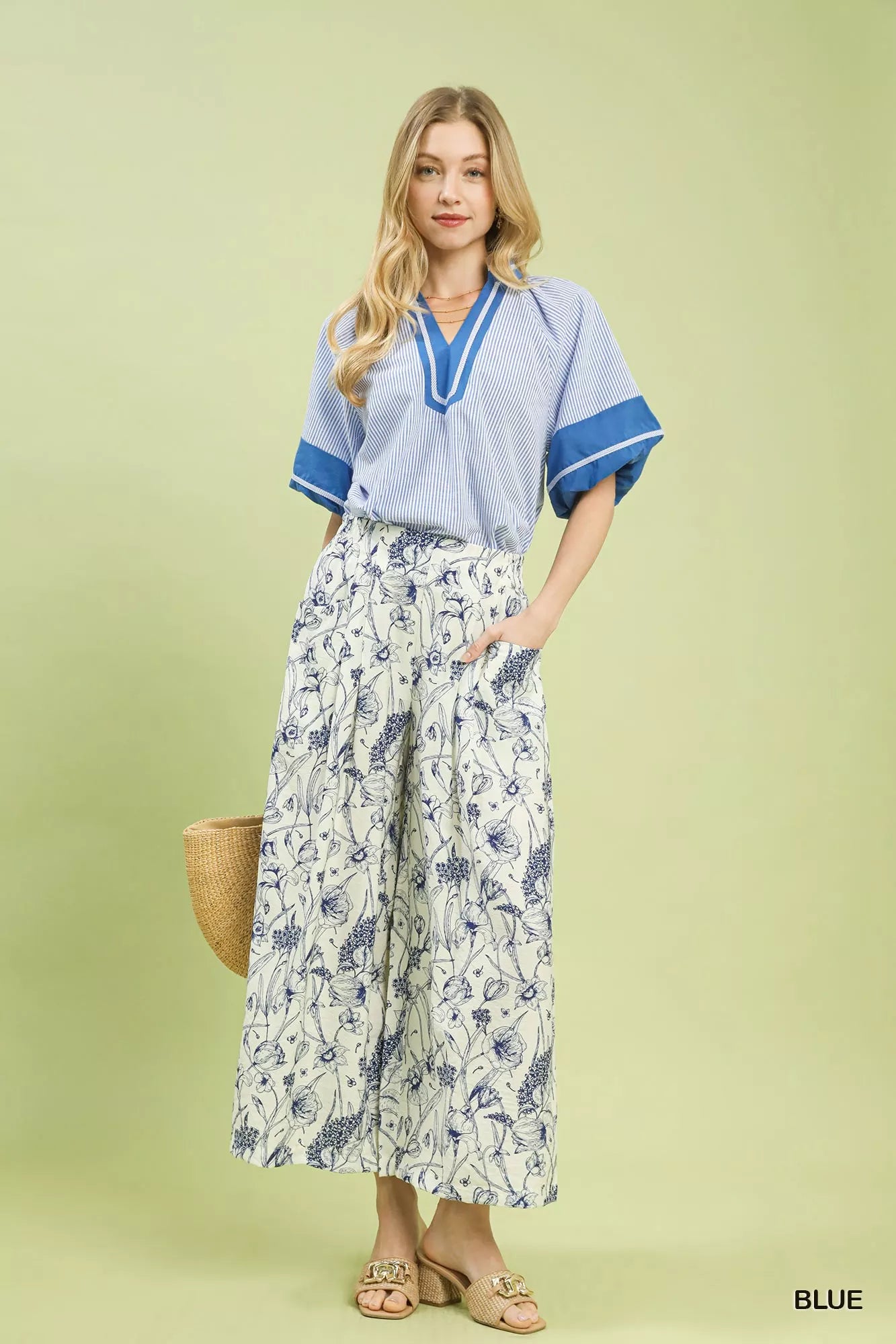Wide-leg pants with blue botanical floral print, pleated design, elastic waistband, and relaxed fit on a light background