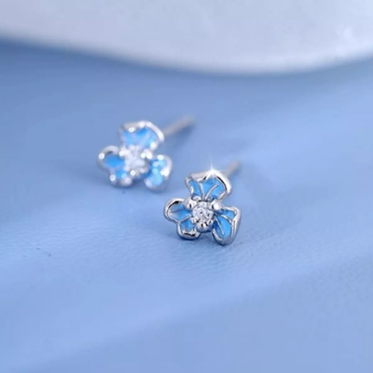 Sterling silver floral stud earrings with blue enamel petals