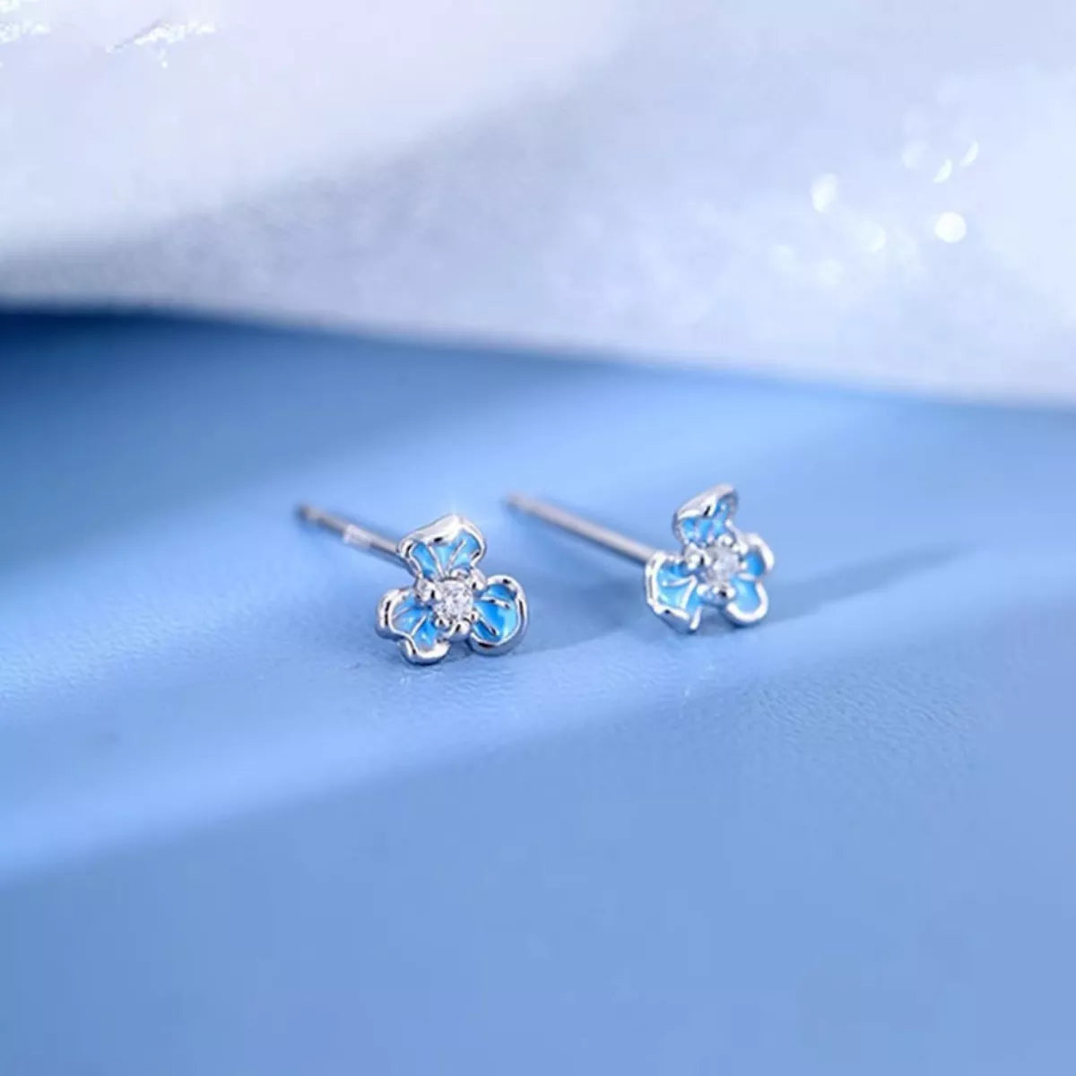 Sterling silver floral stud earrings with blue enamel petals