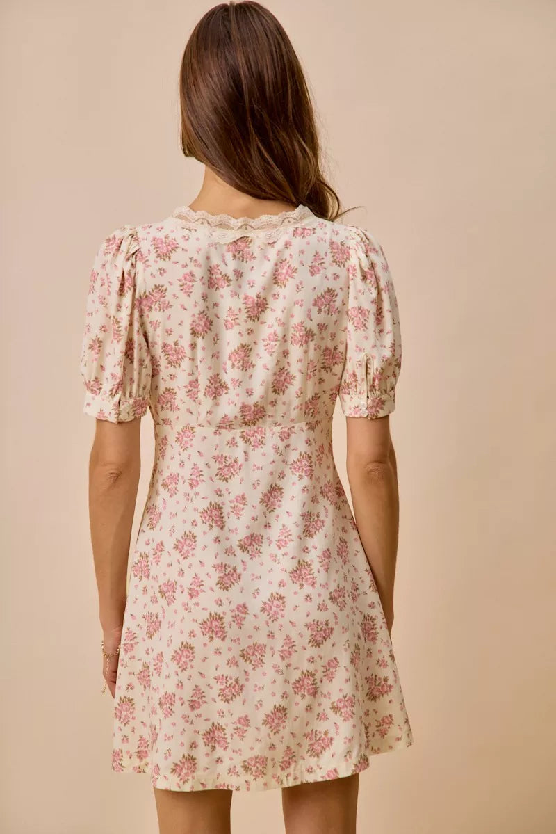 Cream floral mini dress with lace-trim neckline, front bow detail, short sleeves, and romantic vintage-inspired print