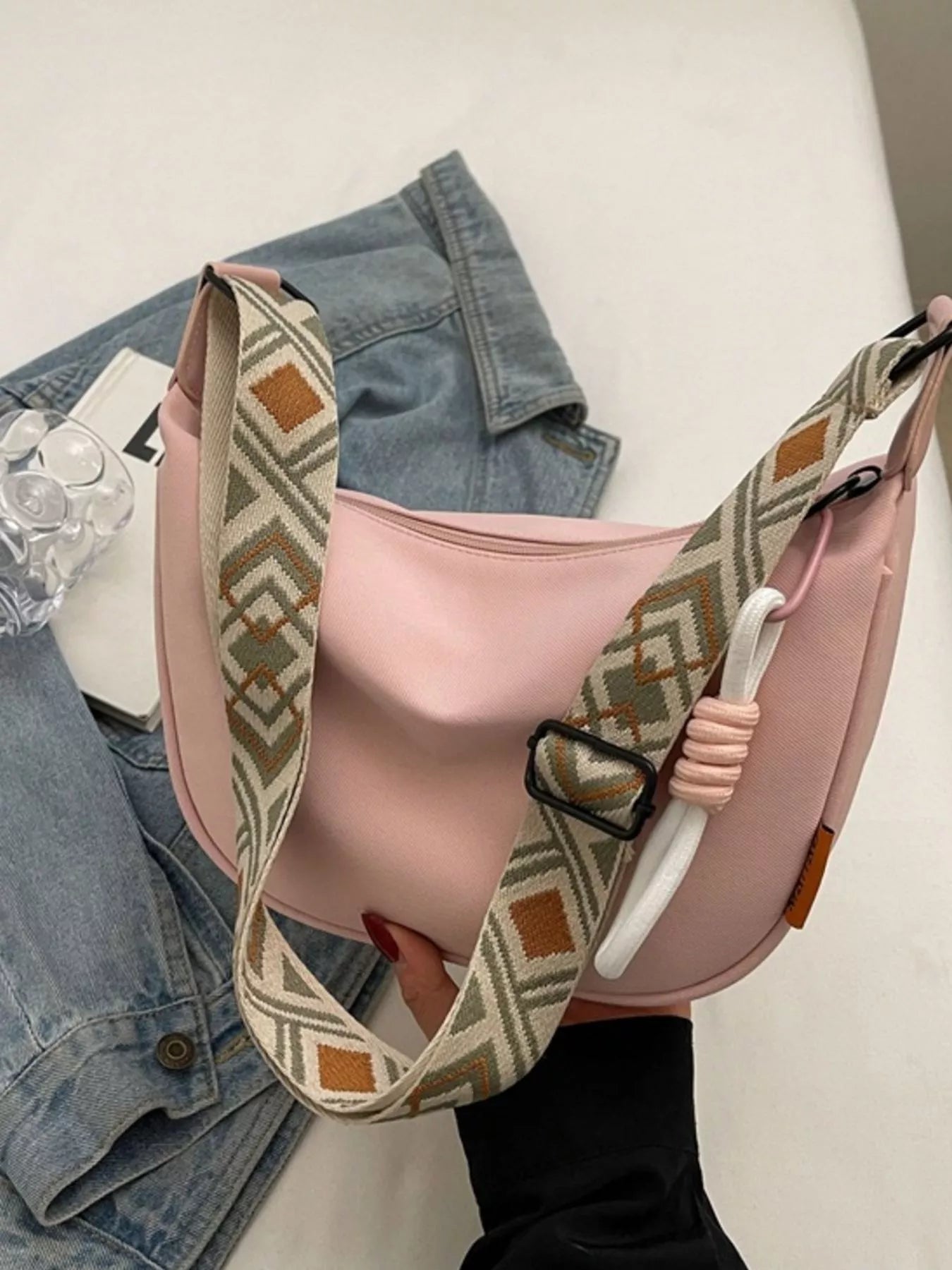 Blush canvas crossbody bag with adjustable geometric strap displayed on a tabletop for everyday styling