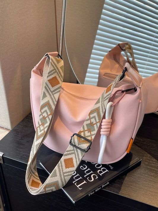 Blush canvas crossbody bag with adjustable geometric strap displayed on a tabletop for everyday styling