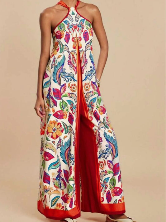 Model wearing red multicolor Boho Breeze Halter Jumpsuit with floral and leaf print, wide-leg design, and halter neckline.