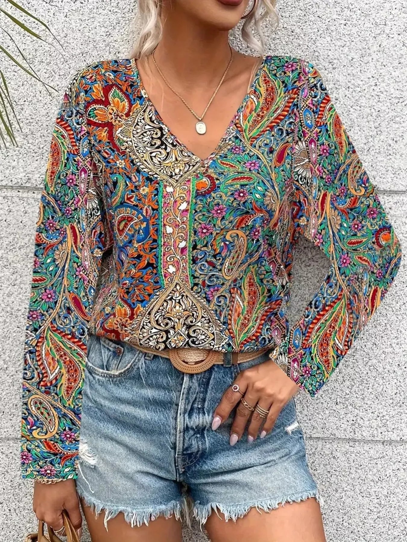Boho paisley patchwork blouse with a V-neckline, flowy long sleeves, and relaxed slightly stretchy fit styled with denim shorts.