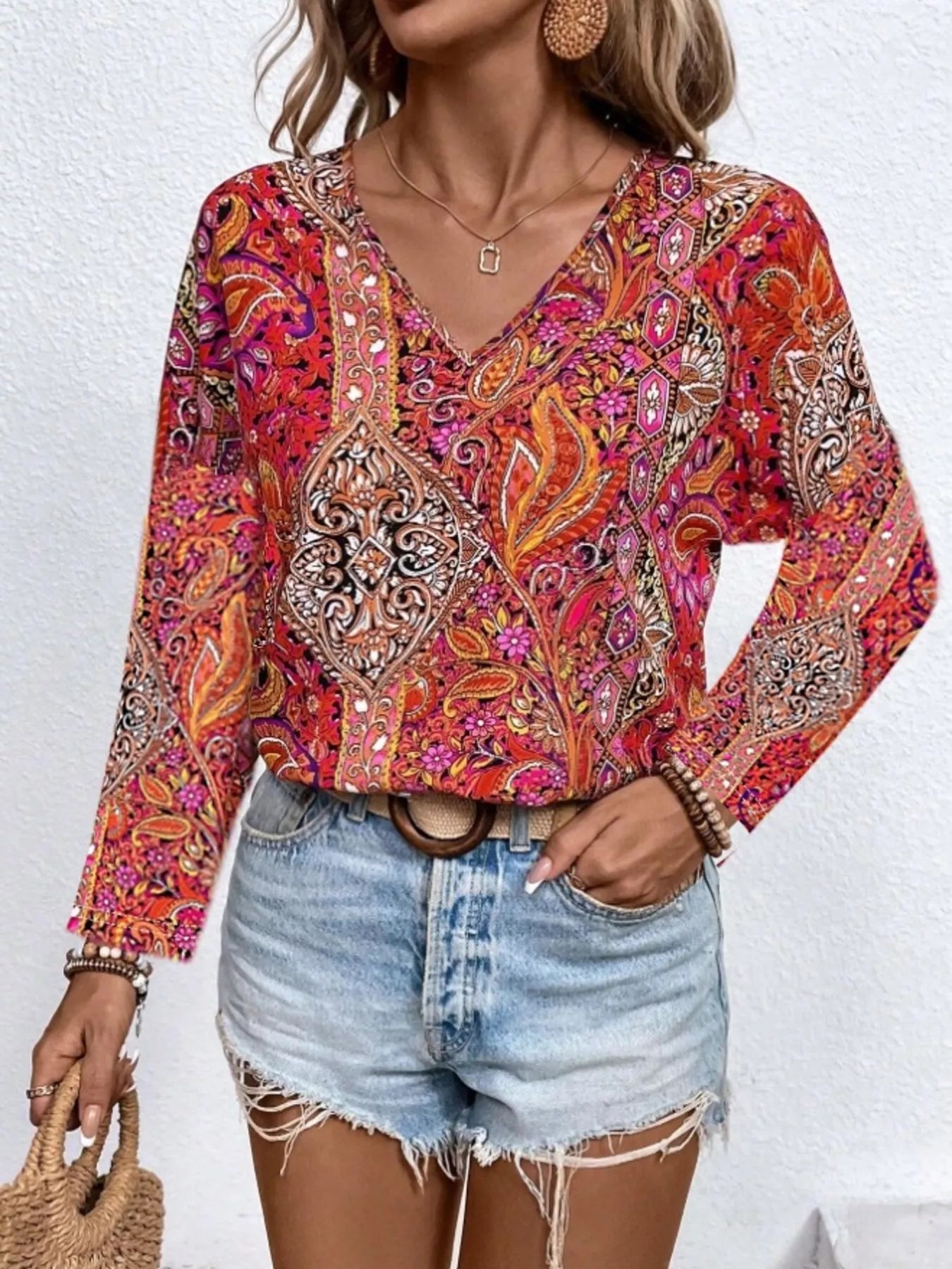 Boho paisley patchwork blouse with a V-neckline, flowy long sleeves, and relaxed slightly stretchy fit styled with denim shorts.