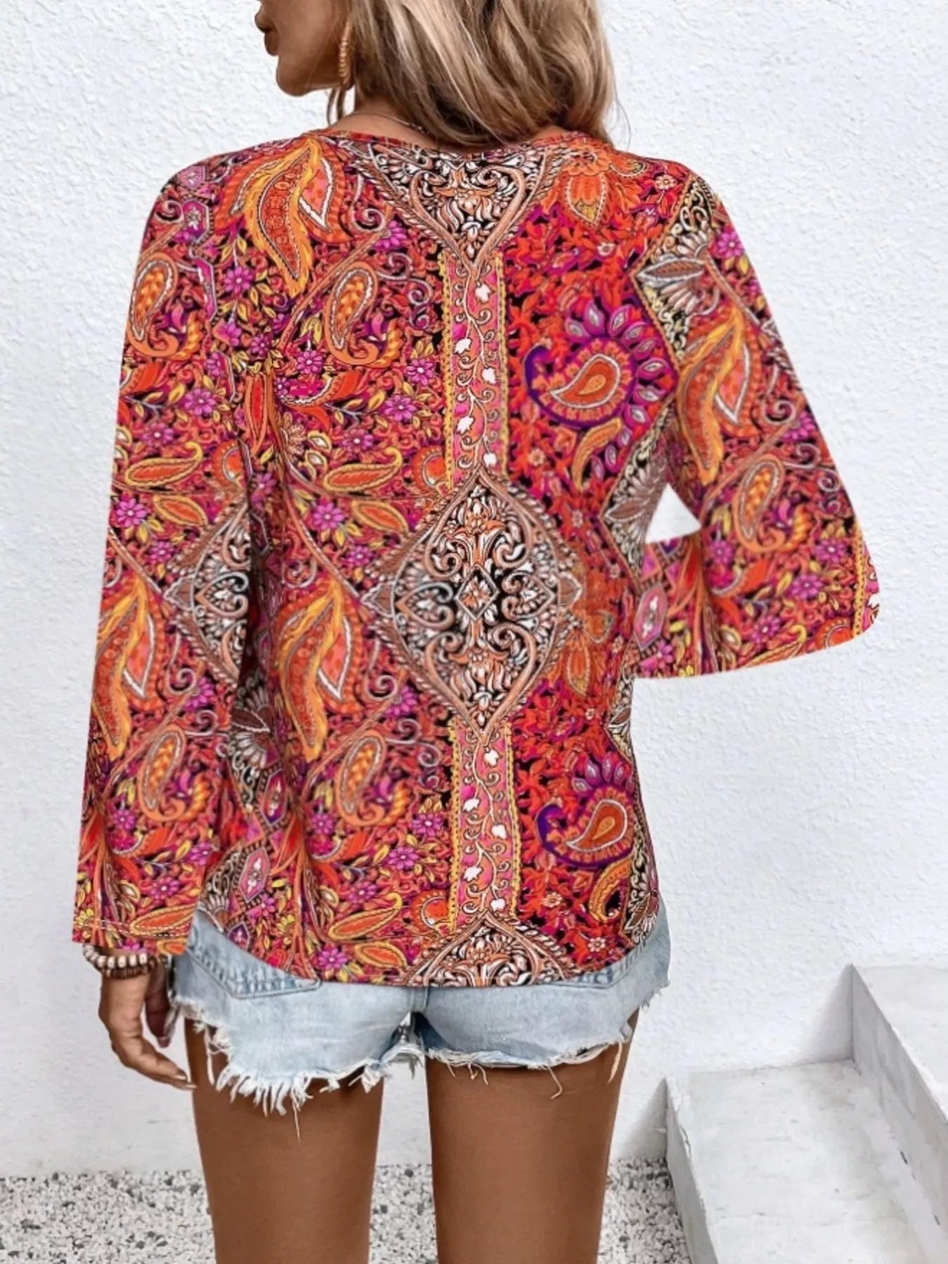 Boho paisley patchwork blouse with a V-neckline, flowy long sleeves, and relaxed slightly stretchy fit styled with denim shorts.