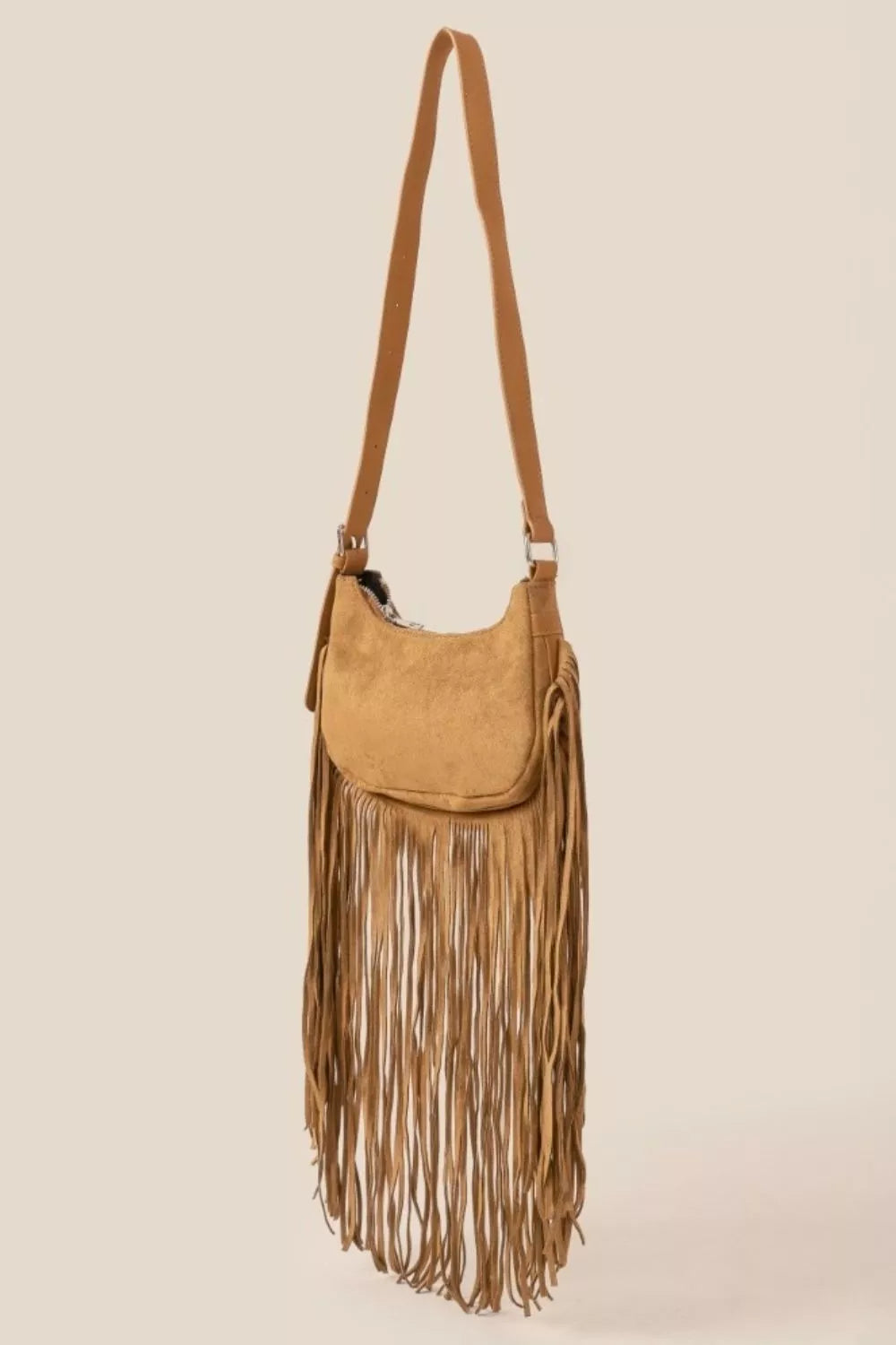 Tan suede crossbody bag with long fringe detailing and boho-inspired design.