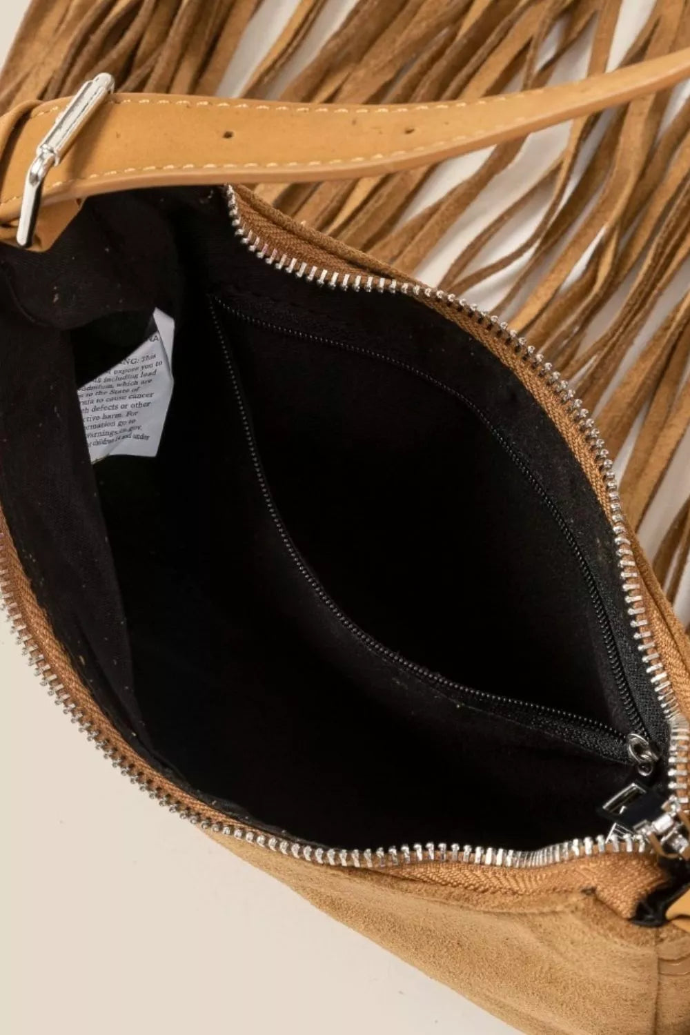 Tan suede crossbody bag with long fringe detailing and boho-inspired design.