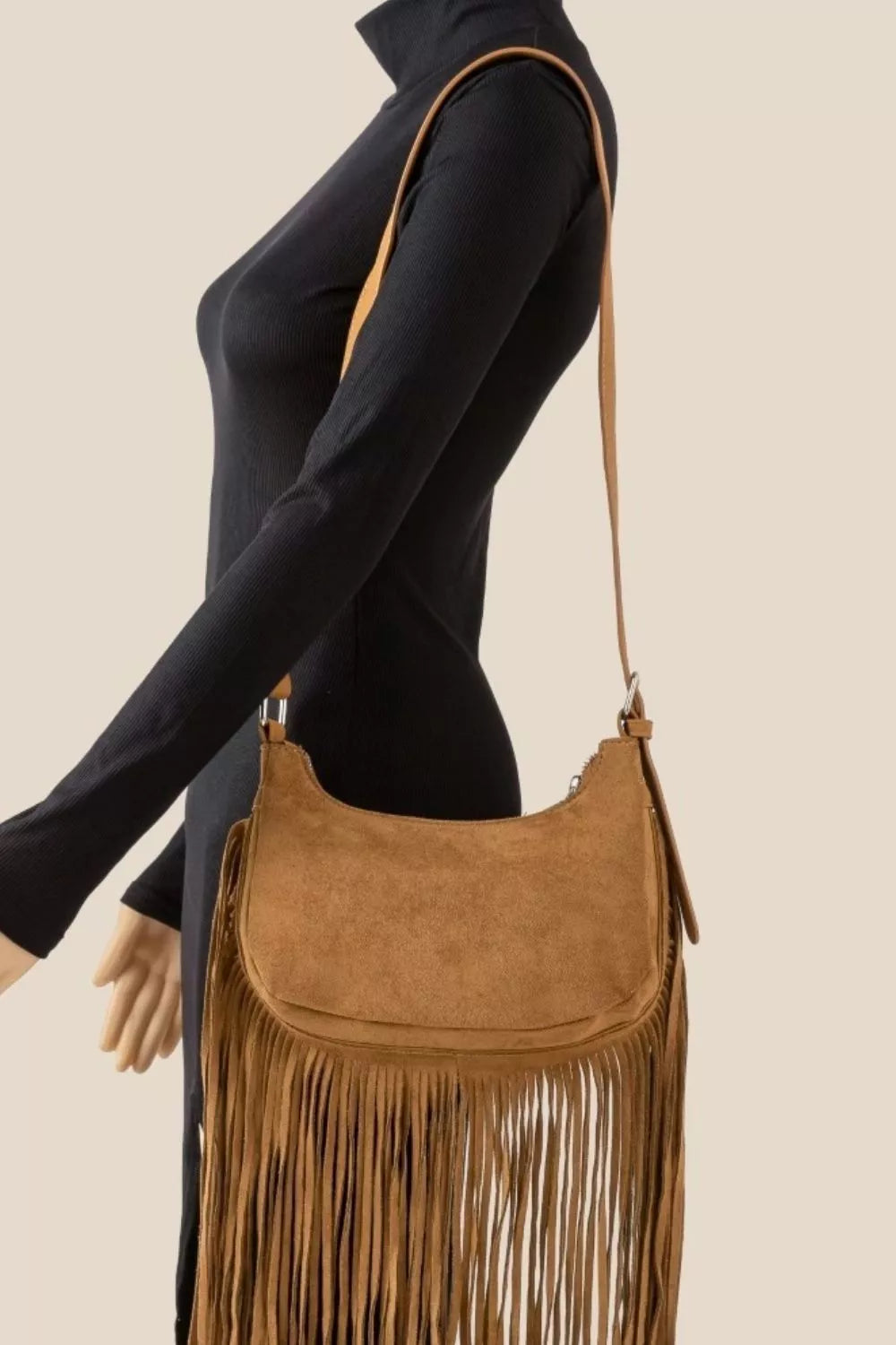 Tan suede crossbody bag with long fringe detailing and boho-inspired design.