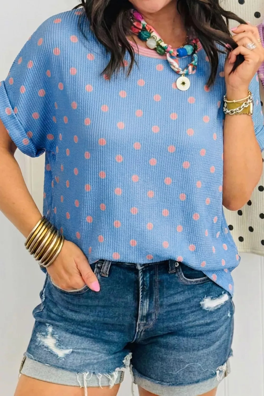 Blue short sleeve top with pink polka dots, textured fabric, and a relaxed slightly stretchy fit.
