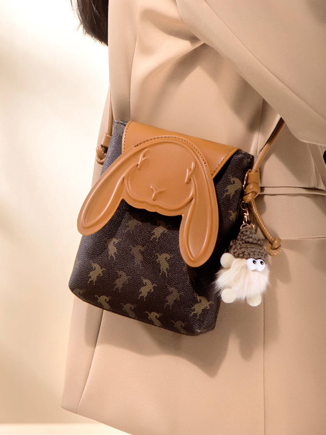 Mini crossbody bag with bunny ear flap design worn with neutral outfit