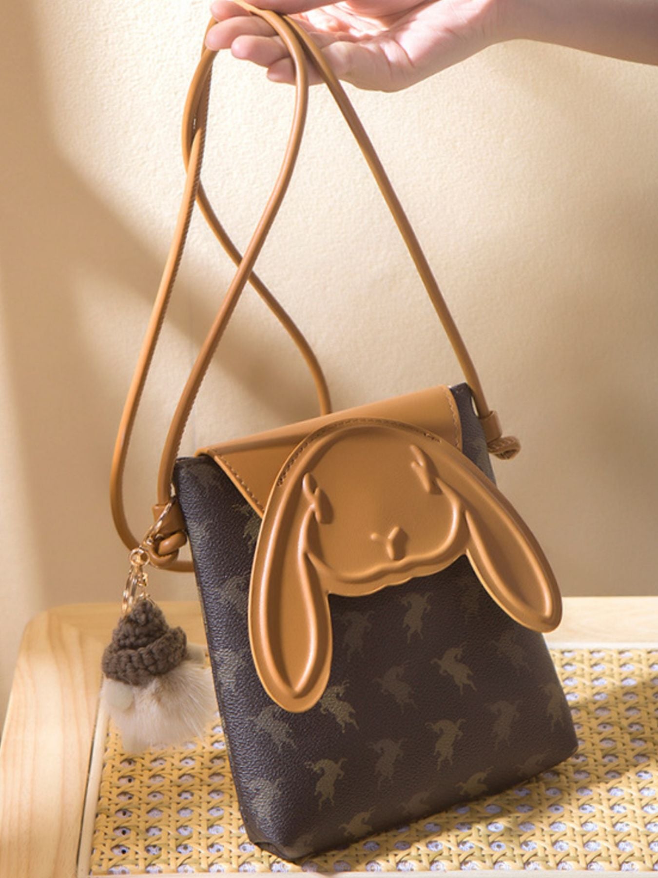 Mini crossbody bag with bunny ear flap design worn with neutral outfit