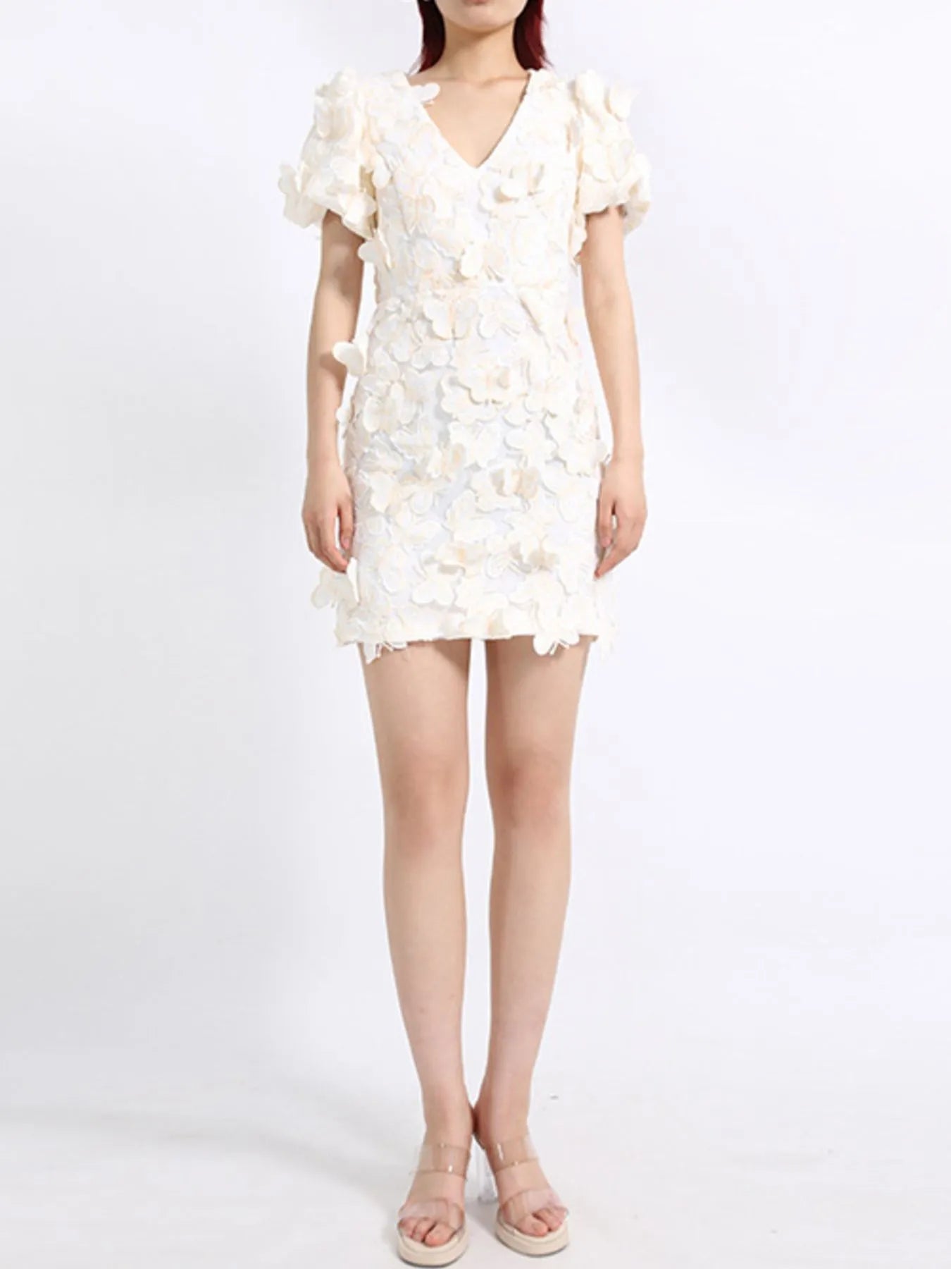 Model wearing a white mini dress adorned with 3D butterfly appliqués, featuring short puff sleeves, a V-neckline, and a fitted silhouette, styled against a plain background.