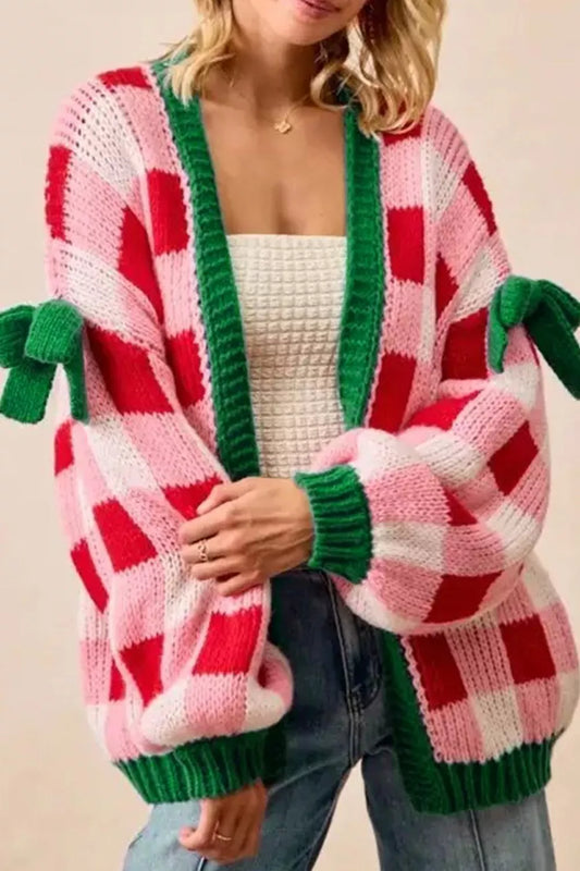 Festive pink and red checker knit cardigan with green trim and bow details on sleeves.