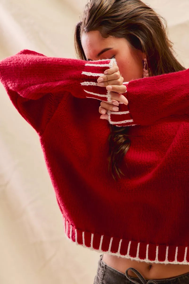 Woman wearing a red sweater with white contrast stitching along the collar, cuffs, and hem — cozy holiday sweater from A Whimsical Affair.