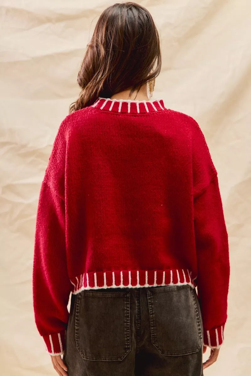 Woman wearing a red sweater with white contrast stitching along the collar, cuffs, and hem — cozy holiday sweater from A Whimsical Affair.