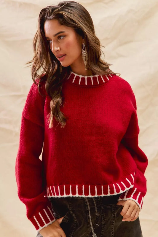 Woman wearing a red sweater with white contrast stitching along the collar, cuffs, and hem — cozy holiday sweater from A Whimsical Affair.
