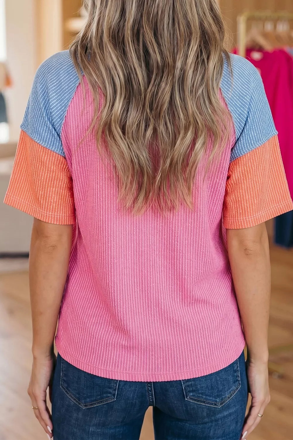 Color block ribbed V-neck tee with pink body, blue shoulders, orange sleeves, seam details, and slightly stretchy fit.
