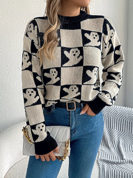 Woman wearing a black checkerboard knit sweater with ghost pattern, styled with jeans and a white purse — cozy Halloween sweater from A Whimsical Affair.