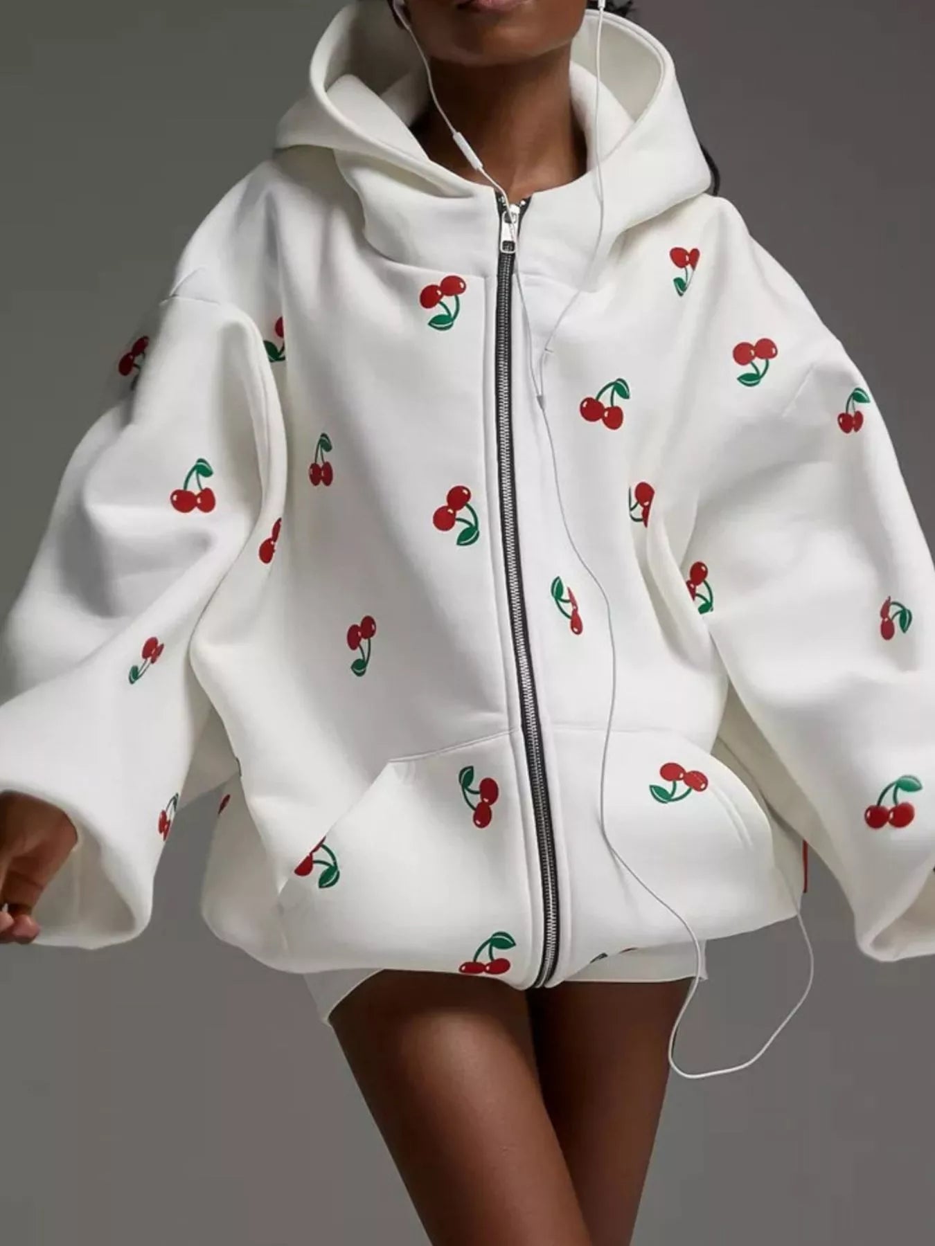 Model wearing a white oversized zip hoodie featuring red cherry embroidery and a front pocket, styled for a cute streetwear look.