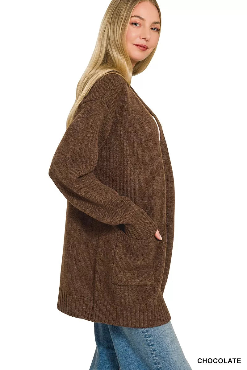 Open-front knit cardigan with front pockets, ribbed trim, long sleeves, and a relaxed slightly stretchy fit styled with jeans.