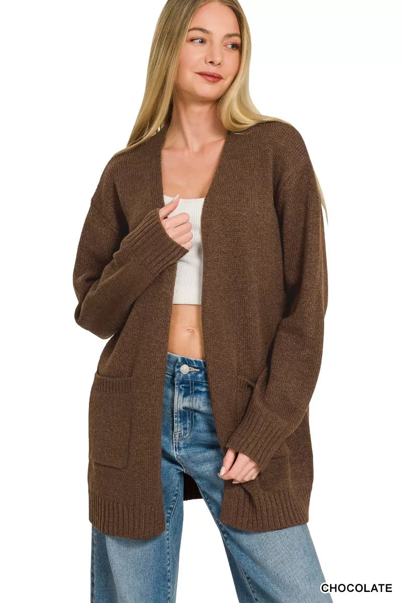 Open-front knit cardigan with front pockets, ribbed trim, long sleeves, and a relaxed slightly stretchy fit styled with jeans.