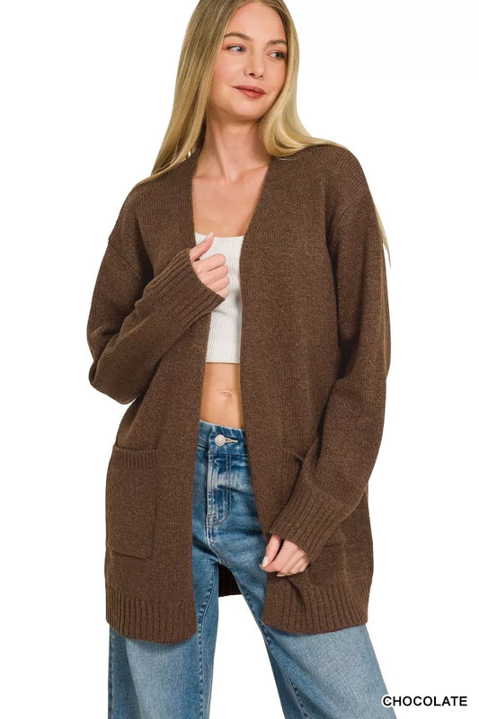 Open-front knit cardigan with front pockets, ribbed trim, long sleeves, and a relaxed slightly stretchy fit styled with jeans.