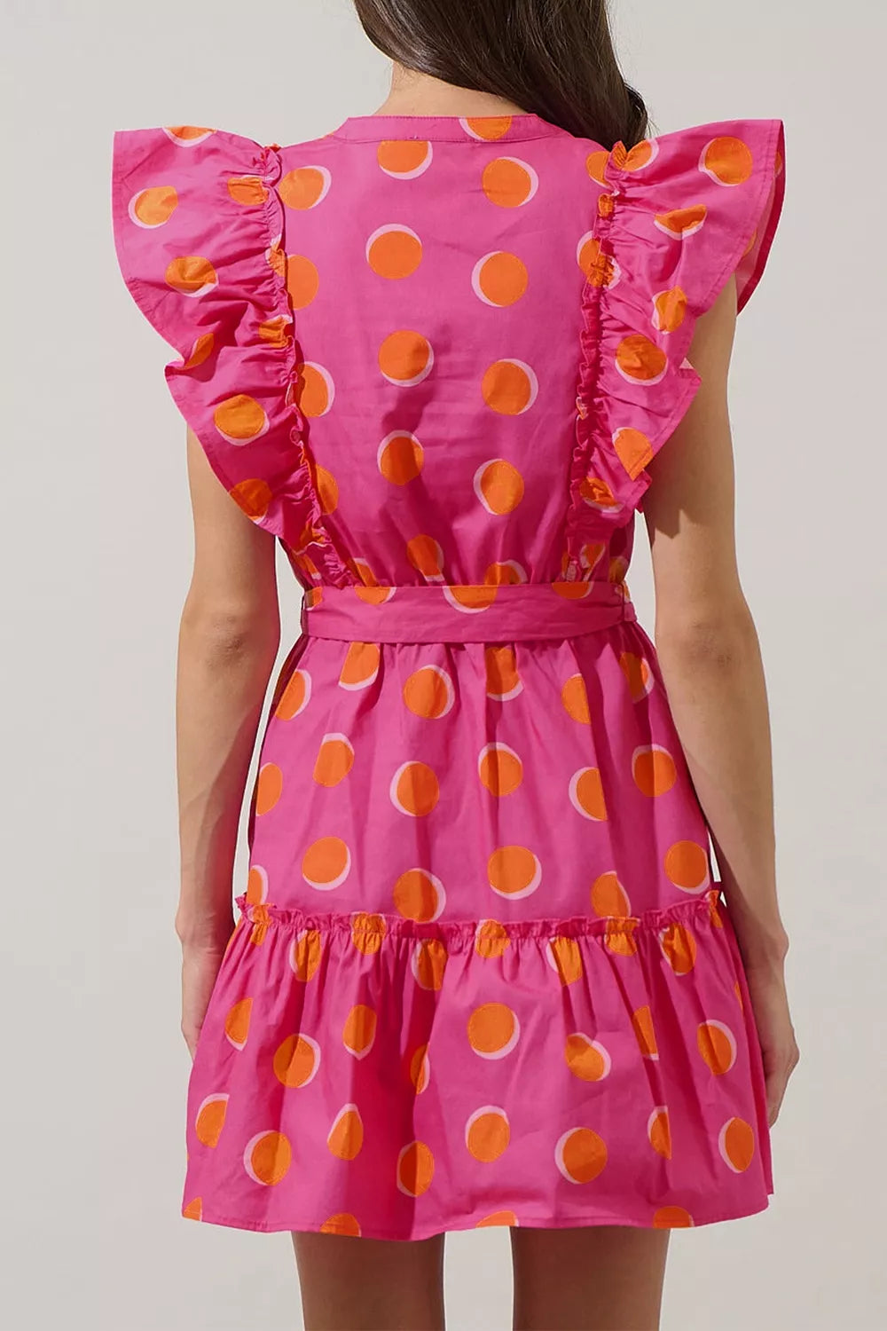 Bright polka dot mini dress with ruffled sleeves, belted waist, tiered skirt, and playful statement style.