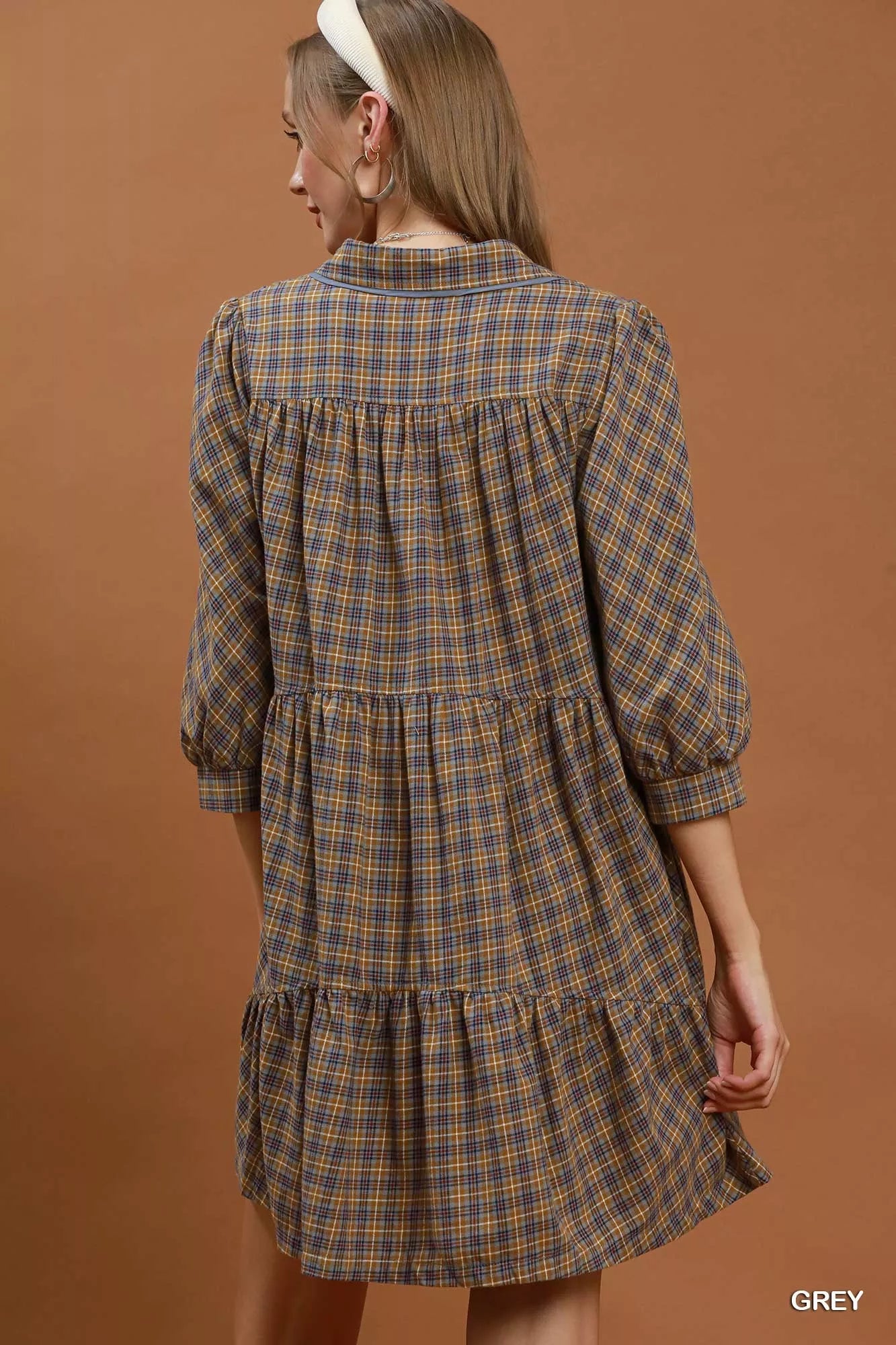 Oversized plaid button-down shirt dress with collared neckline, pocket detail, long sleeves, and relaxed cotton fit styled with a crossbody bag.