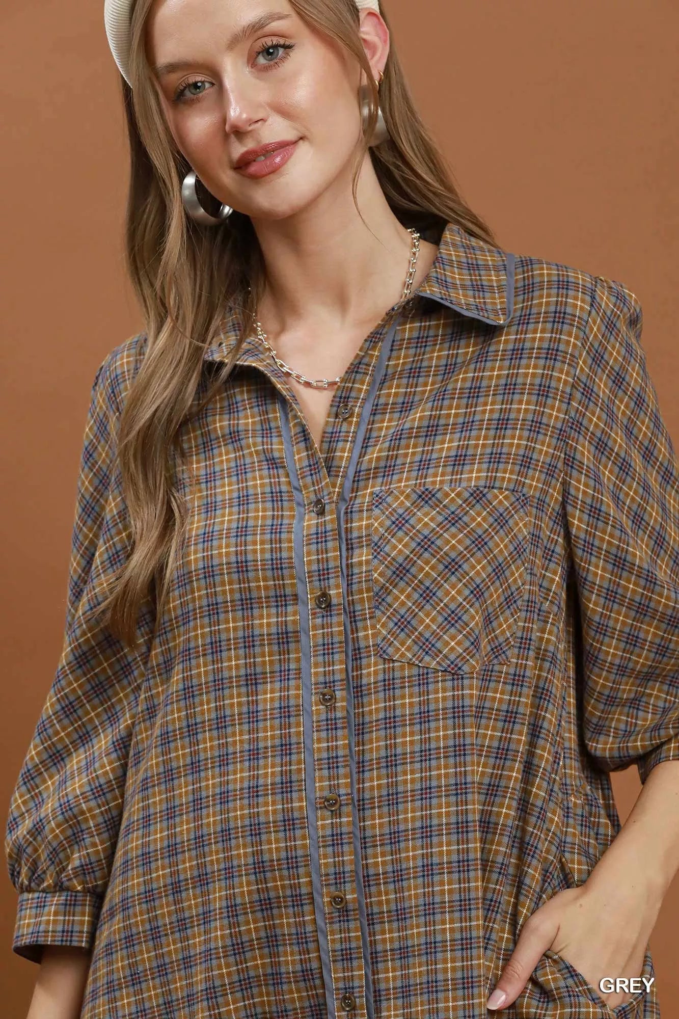 Oversized plaid button-down shirt dress with collared neckline, pocket detail, long sleeves, and relaxed cotton fit styled with a crossbody bag.