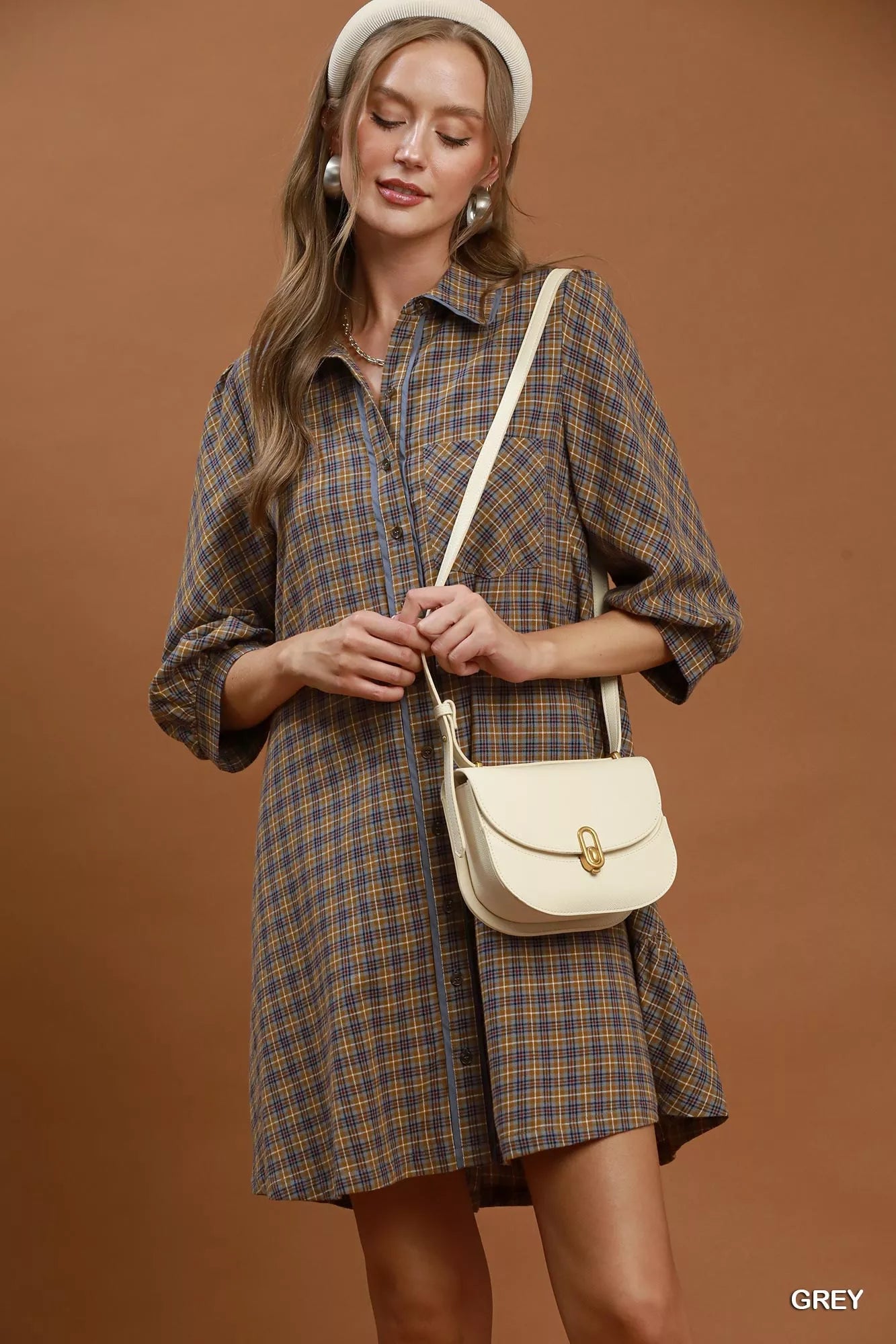 Oversized plaid button-down shirt dress with collared neckline, pocket detail, long sleeves, and relaxed cotton fit styled with a crossbody bag.