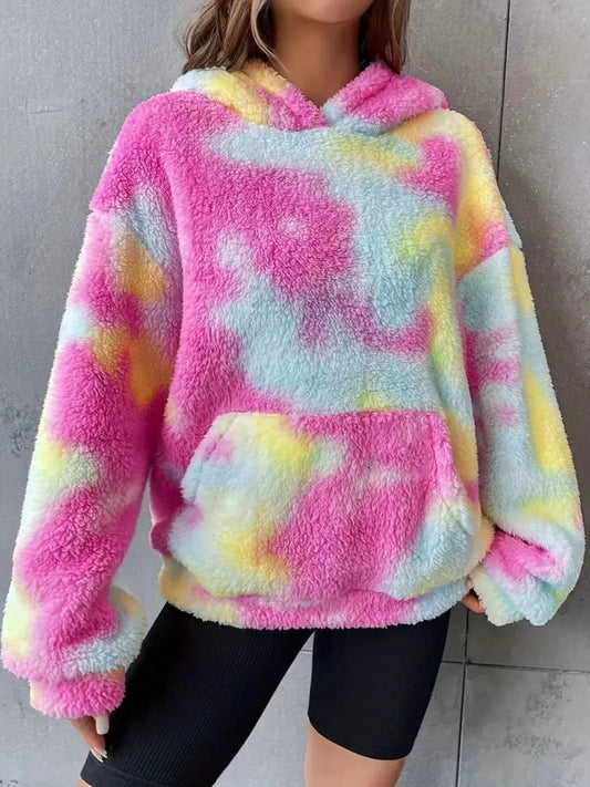 Model wearing a pastel tie-dye plush hoodie in pink, blue, and yellow with a kangaroo pocket and oversized cozy fit.