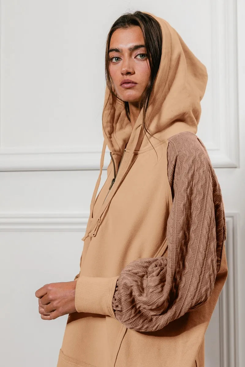 Woman wearing a beige French terry hoodie with knit sleeves and a half-zip front for a cozy, casual look.
