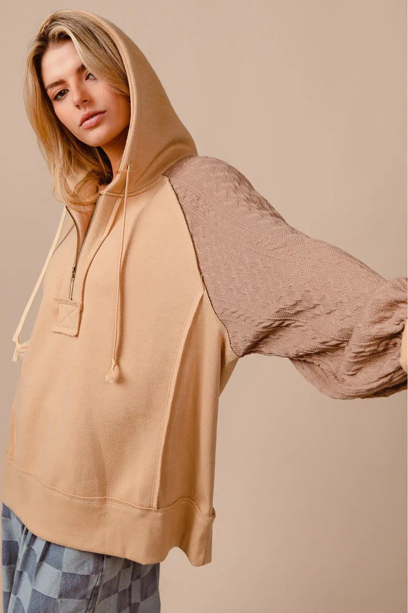 Woman wearing a beige French terry hoodie with knit sleeves and a half-zip front for a cozy, casual look.