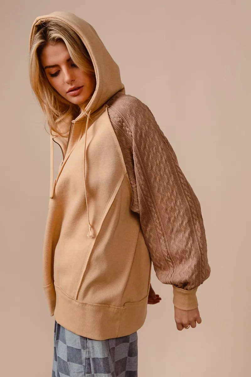 Woman wearing a beige French terry hoodie with knit sleeves and a half-zip front for a cozy, casual look.