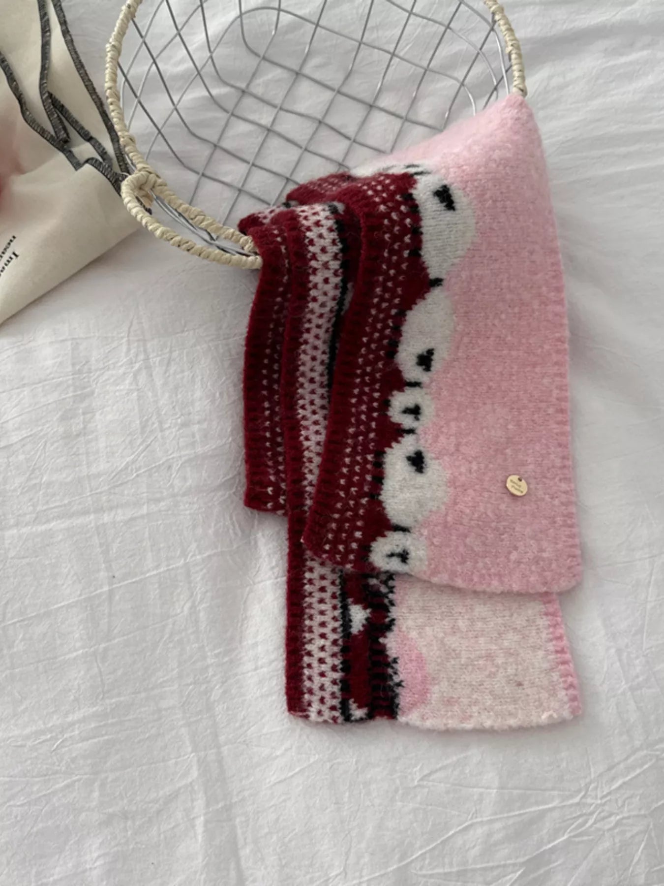 Soft knit scarf featuring a whimsical sheep pattern laid out on a neutral fabric background