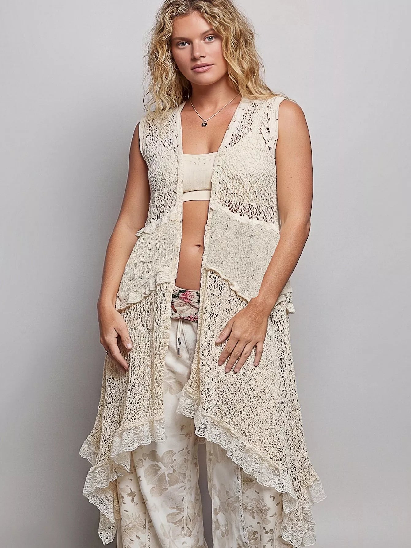 Sleeveless crochet vest with openwork texture, lace details, cascading ruffle hem, and lightweight boho layering style.