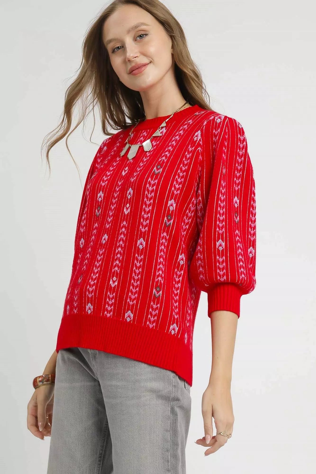 Woman wearing the Crimson Cascade Sweater in bold red with jacquard knit pattern and puff sleeves.