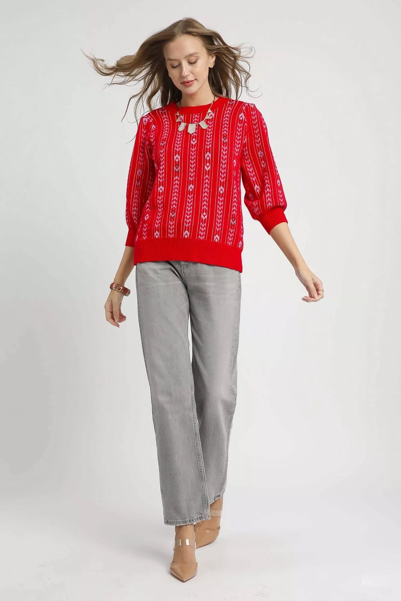 Woman wearing the Crimson Cascade Sweater in bold red with jacquard knit pattern and puff sleeves.