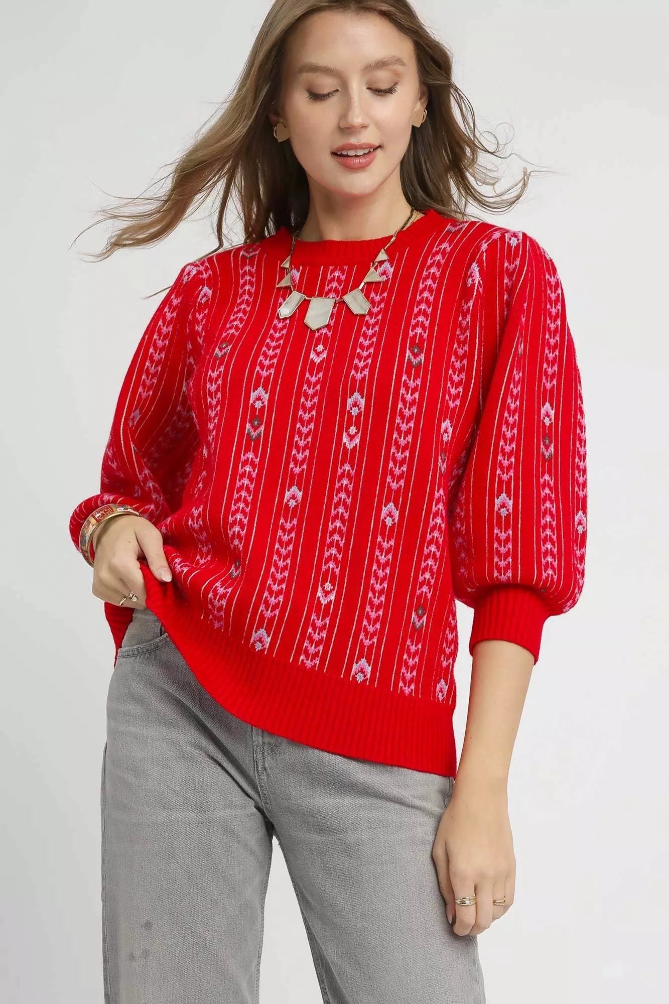 Woman wearing the Crimson Cascade Sweater in bold red with jacquard knit pattern and puff sleeves.