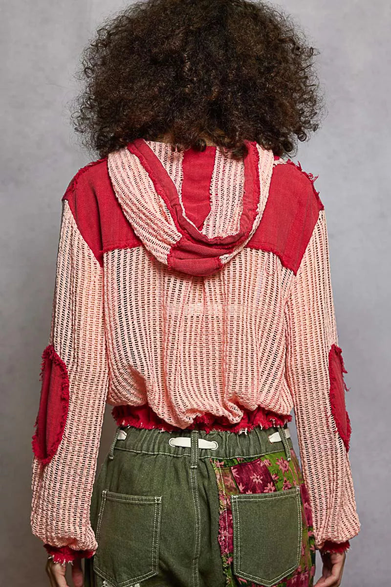 Model wearing a red and pink woven hooded button-down shirt with patch pockets and drawstring hem, styled with boho pants.