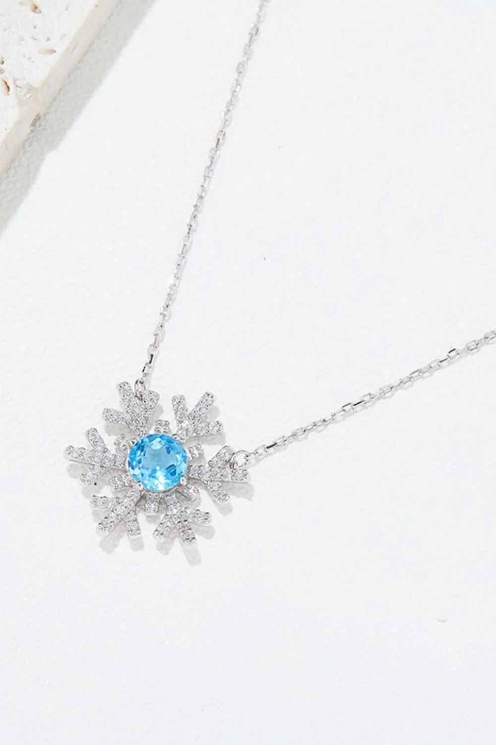 Sterling silver snowflake pendant necklace with a topaz center stone.