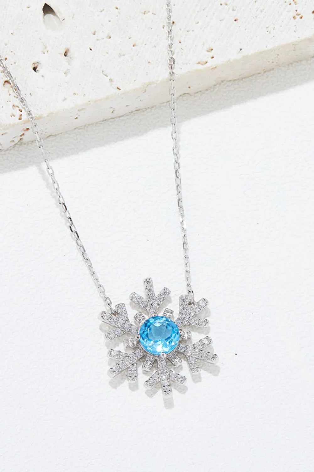 Sterling silver snowflake pendant necklace with a topaz center stone.