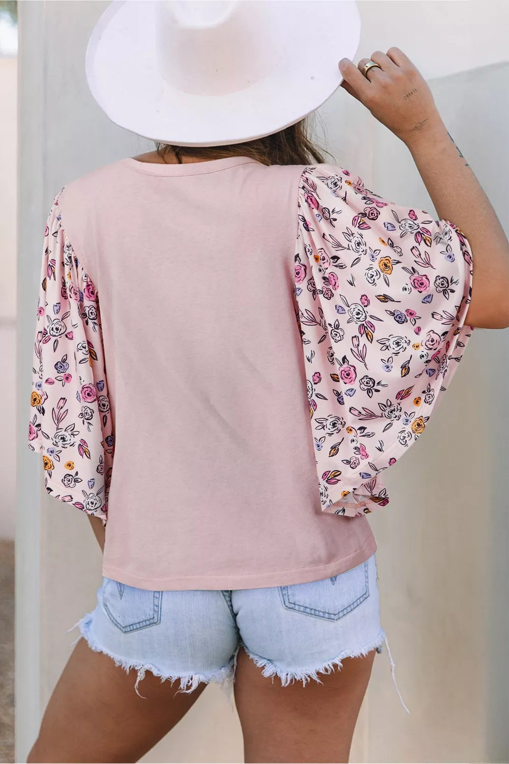 Light pink tee with floral puff sleeves and an oversized floral appliqué on the front styled with denim shorts.